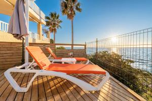 two chairs and an umbrella on a deck with the ocean at Casa L´Augusta II, Casa sobre el mar en Altafulla in Altafulla