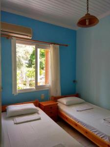 two beds in a room with a window at Kostas Studios II in Vasiliki
