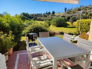 einen weißen Tisch und Stühle auf einer Terrasse mit Grill in der Unterkunft Jardines De La Torre in Benahavís