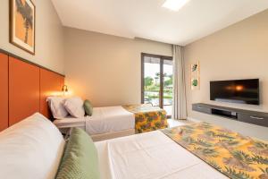 um quarto de hotel com duas camas e uma televisão de ecrã plano em Reserva dos Lagos By Nobile - Boa Luz em Laranjeiras