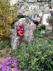 a sign on a rock in a garden with flowers at Weingut & Gastehaus Andreas Erz in Brauneberg