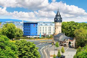 Un edificio con una torre dell'orologio nel centro di una città di Best Western Premier IB Hotel Friedberger Warte a Francoforte sul Meno