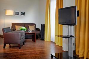 - un salon avec une télévision et un canapé dans l'établissement Best Western Premier IB Hotel Friedberger Warte, à Francfort-sur-le-Main