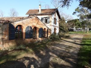 una vieja casa de ladrillo con puertas negras y un camino en Le Chais, en Villemur-sur-Tarn