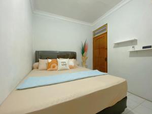 um quarto branco com uma cama grande e almofadas em Yoda Yosandra Homestay em Timuran