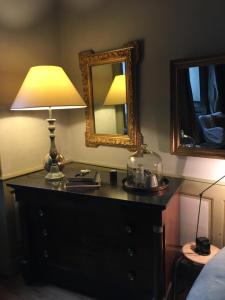 1 dormitorio con tocador con lámpara y espejo en La Maison d'A Côté en Pontarlier