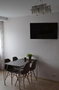 a dining room table with chairs and a tv on a wall at Šaulys1 in Druskininkai