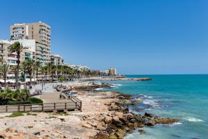 a beach with buildings and the ocean with people on it at Studio Playa del Cura in Torrevieja