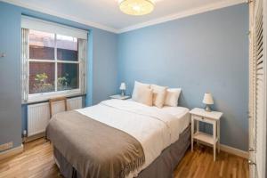 een blauwe slaapkamer met een groot bed en een raam bij Cosy 2 Bedroom Apartment in Bayswater in Londen