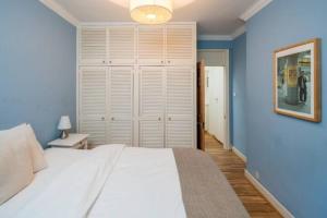 een slaapkamer met een groot wit bed en blauwe muren bij Cosy 2 Bedroom Apartment in Bayswater in Londen
