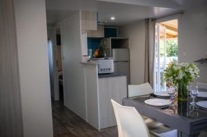 Foulerot的住宿－Mobil Home XXL 4 chambres - Camping Le Domaine d'Oléron，厨房以及带桌椅的用餐室。