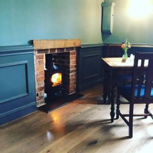 a fireplace in a room with a table and a chair and a table sidx sidx at The Boyne Arms in Burwarton