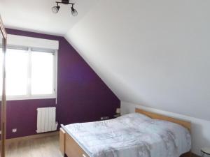 1 dormitorio con cama y pared púrpura en Semi-detached house, Bréhal, en Bréhal