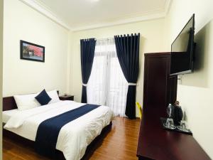 een slaapkamer met een bed en een flatscreen-tv bij Bách Thảo Hotel in Da Lat