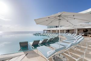 a pool with chairs and an umbrella and the ocean at Sun Palace - All Inclusive in Cancún