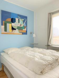 un letto bianco in una camera da letto con un dipinto sul muro di ApartmentInCopenhagen Apartment 700 a Copenaghen