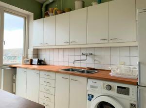 una cucina con armadietti bianchi e lavatrice di ApartmentInCopenhagen Apartment 700 a Copenaghen