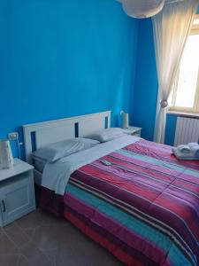a blue bedroom with a bed with a rainbow blanket at Casa Castellano in Nola