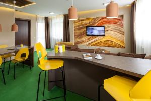 a restaurant with yellow chairs and a large painting on the wall at Aparthotel Gutinului in Cluj-Napoca