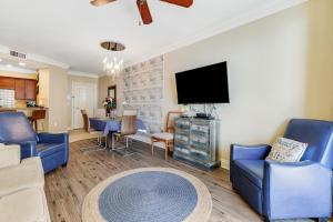 a living room with blue chairs and a flat screen tv at Emerald Grande 922 in Destin