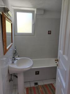 y baño blanco con lavabo y bañera. en Villa Myrto - Beautiful see-view villa, en Stafylos
