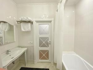 ein weißes Bad mit einem Waschbecken und einer Dusche in der Unterkunft Kikasso Art Apart Odessa in Fontanka