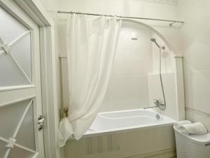 a white bath tub with a shower curtain in a bathroom at Kikasso Art Apart Odessa in Fontanka