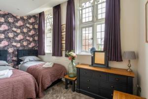 1 Schlafzimmer mit 2 Betten und einem TV auf einer Kommode in der Unterkunft Idyllic city centre apartment in Canterbury in Kent