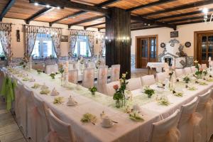 uma mesa longa com mesas brancas e cadeiras num quarto em Waldhotel Dietrichsmühle em Crottendorf