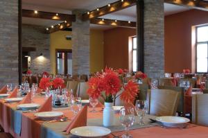 una sala da pranzo con un lungo tavolo con fiori rossi di Sarlóspuszta Club Hotel a Tatárszentgyörgy