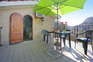 une terrasse avec une table, des chaises et un parasol dans l'établissement Holiday home, Monteggiori, à Santa Lucia