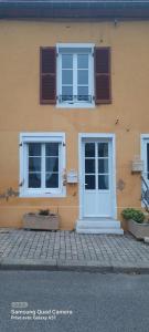 un edificio giallo con due finestre e una porta bianca di Nouveau à Cuisery appartement 70m2 a Cuisery