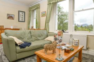 Uma menina numa sala com um cão de brincar na mesa. em West View em Keswick