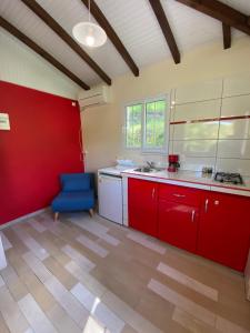 een keuken met rode kasten en een blauwe stoel bij Gite Maya in Émilien