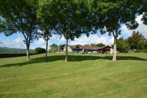 a house in the middle of a field with trees at Kingsley Lake View & Paddocks - A group retreat with hot tub, sports bars & spectacular lake views in the Mendip Hills AONB in Chew Stoke