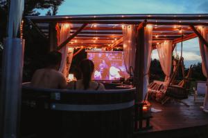 Ein Paar sitzt auf einem Stuhl und schaut sich ein Videospiel an. in der Unterkunft Anahata Siedlisko&Spa in Sejny + 53 Fotos