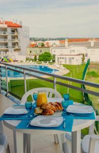 ein Tisch mit einem Teller Essen auf einem Balkon in der Unterkunft Alojamentos Campo & Mar-T2 com Piscina in São Martinho do Porto