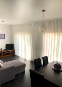 a living room with a couch and a table with chairs at Alojamentos Campo & Mar-T2 com Piscina in São Martinho do Porto