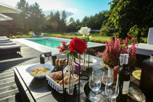 ein Tisch mit Essen und Weingläsern und einem Pool in der Unterkunft Anahata Siedlisko&Spa in Sejny