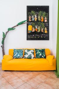 a yellow couch in a living room with a painting on the wall at Nora Guesthouse Rooms and Villas in Pula