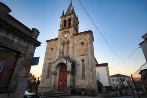 stary kościół z wieżą zegarową na górze w obiekcie Pension Escalinata w mieście Sarria