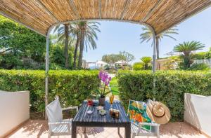 a patio with a table and chairs under a wooden umbrella at Hotel Parco Smeraldo Terme in Ischia