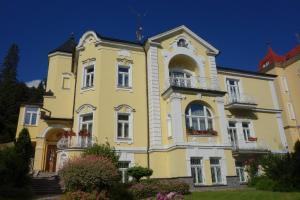 a yellow house with balconies and a blue sky at Villa Sonnenstrahl in Mariánské Lázně