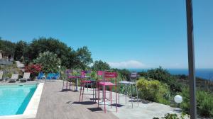 a row of pink chairs and tables next to a swimming pool at Oroverde in Bergeggi