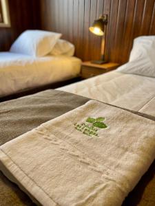 2 Betten mit einem Handtuch mit grüner Pflanze drauf in der Unterkunft Cabañas Las Lengas in Puerto Natales