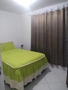 - une chambre avec un lit vert et une fenêtre dans l'établissement Residencial Melodia, à Campos Novos