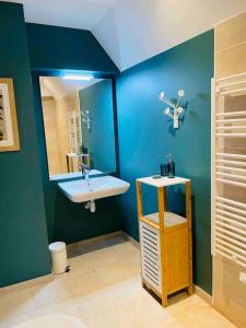 La salle de bains bleue est pourvue d'un lavabo et d'un miroir. dans l'établissement Appartement proche centre historique avec parking, à Sarlat-la-Canéda