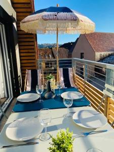 - une table avec des assiettes et un parasol sur le balcon dans l'établissement Appartement proche centre historique avec parking, à Sarlat-la-Canéda