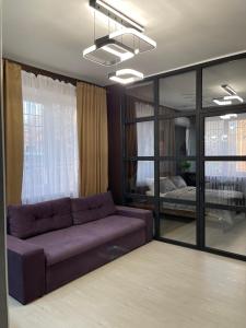 a living room with a purple couch and a bedroom at VEL ЛЮКС in Chernivtsi