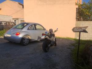 a motorcycle parked next to a small car at Andrebyke terrace in Gergei